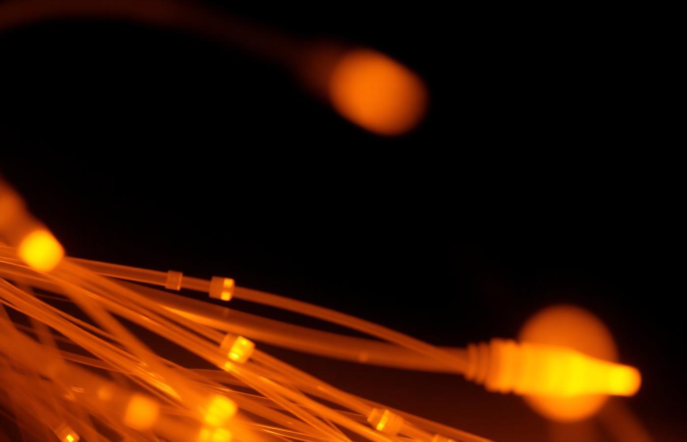 Warm-lit fiber optic strands glowing against a dark background